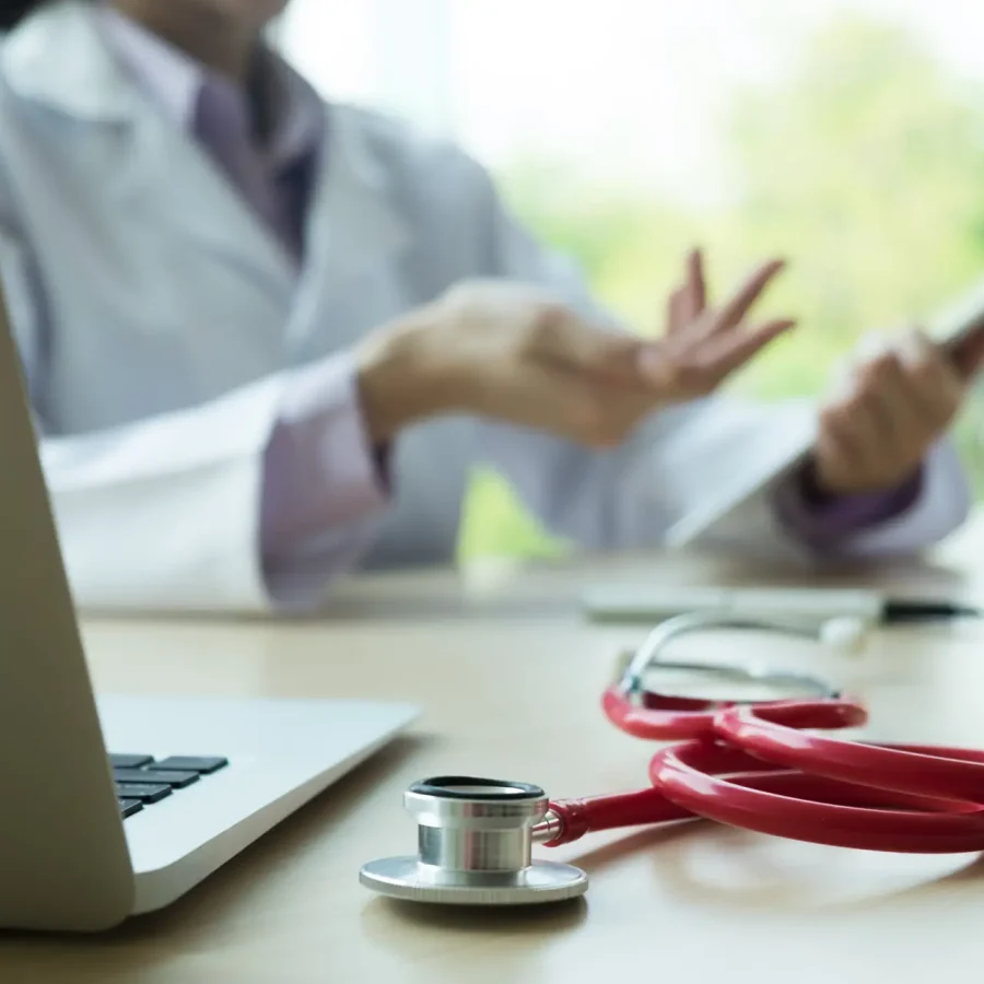 Stethoscope with and Laptop on desk,Doctor working in hospital writing a prescription, Healthcare and medical concept,test results in background.