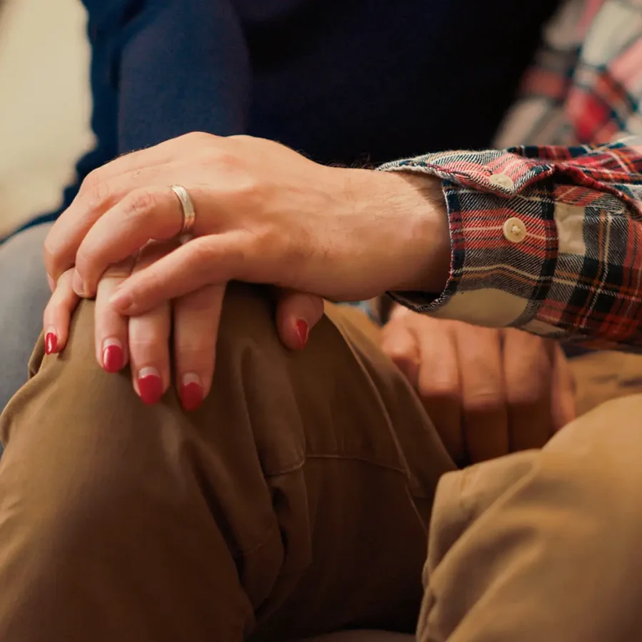 Married couple holding hands after reconciliation at couple therapy session, feeling happy about making peace. Resolving marriage problems with psychotherapist. Close up. Handheld shot.